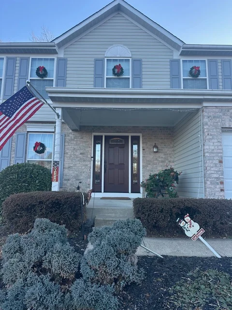 Two-story home with light blue siding, white trim, dark front door, and painted garage door