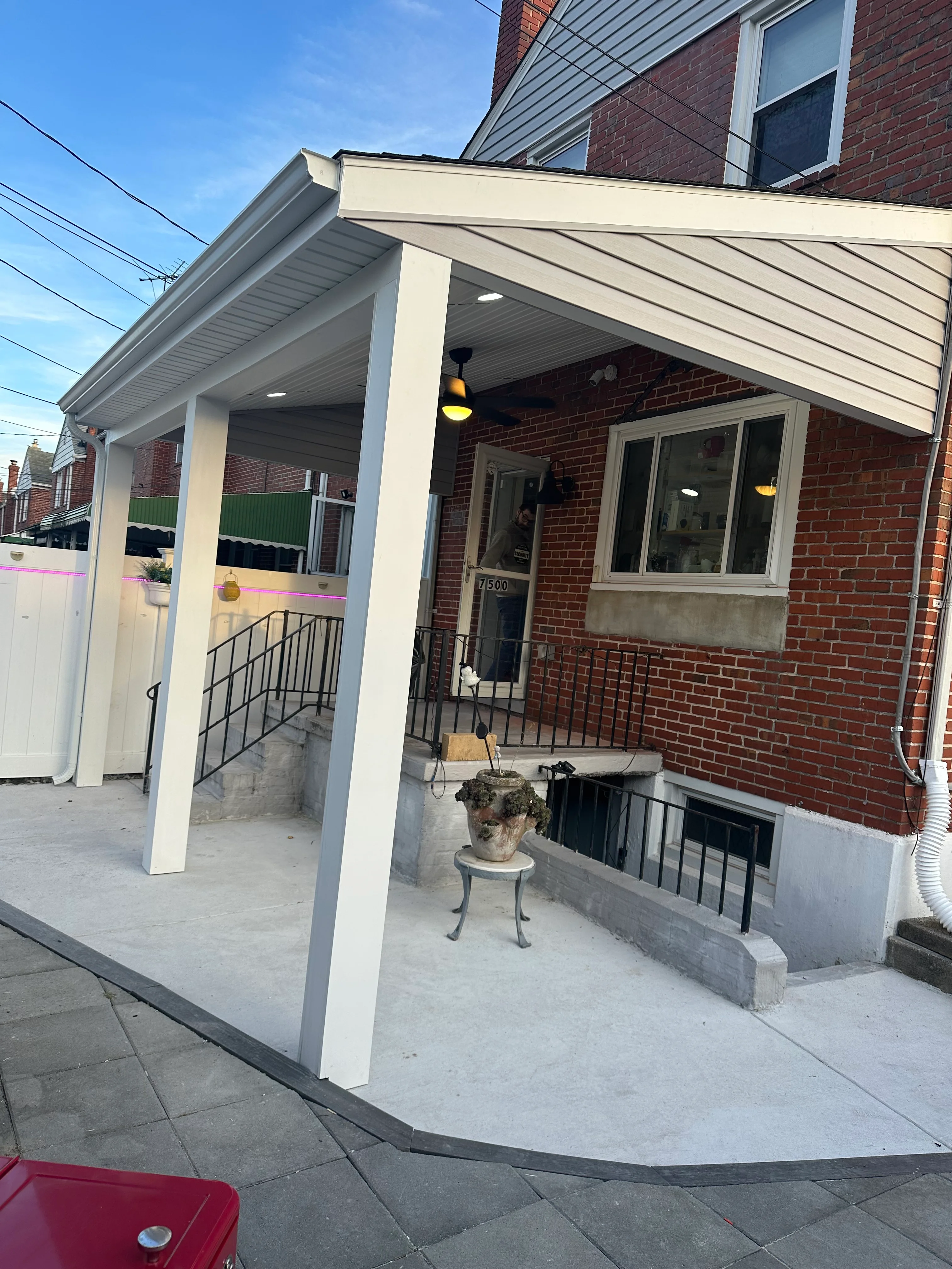 Cream-painted covered porch with white columns and gray soffit on brick home