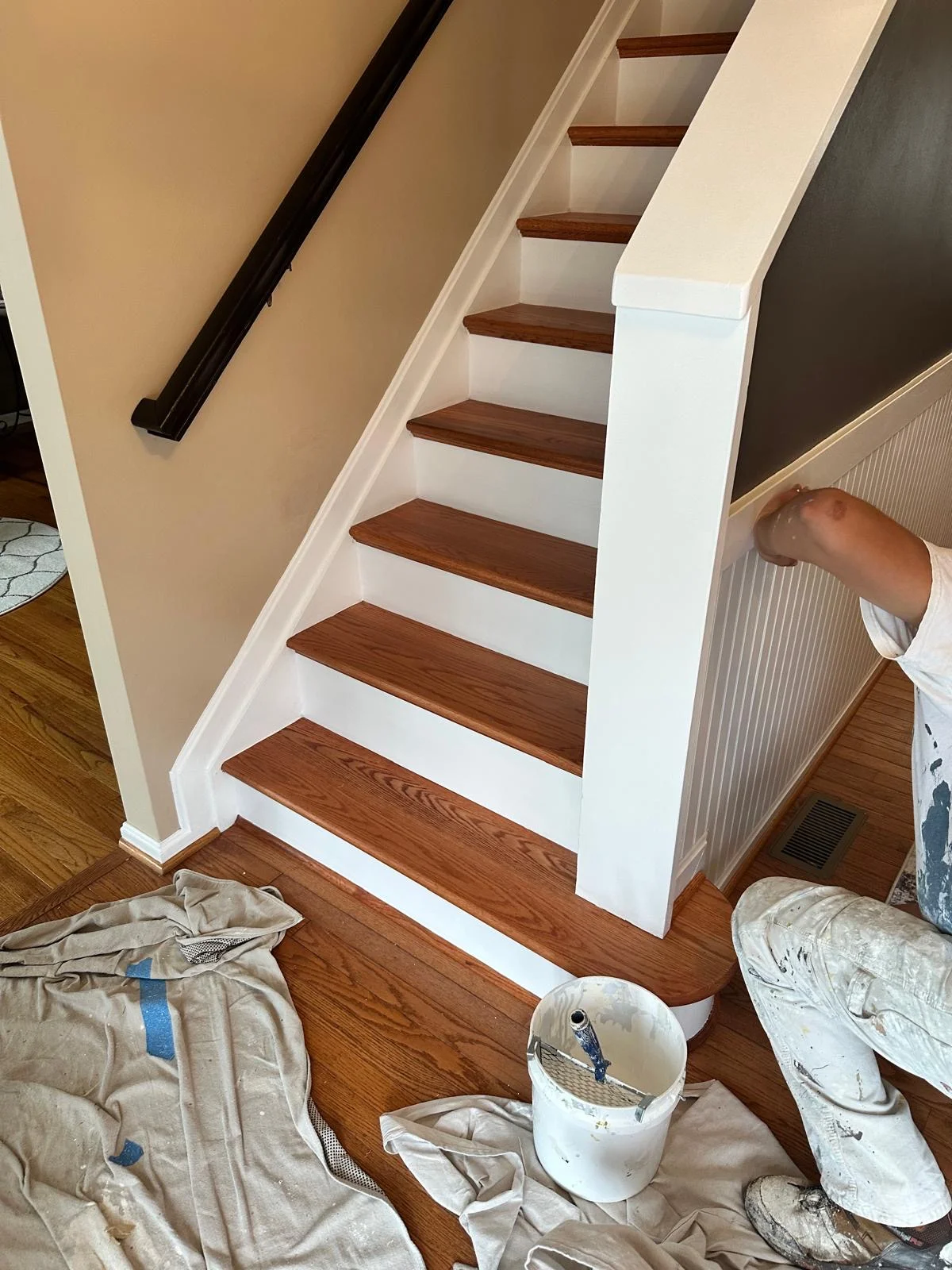 White painted staircase with dark wood treads, black handrail, and neutral wall trim