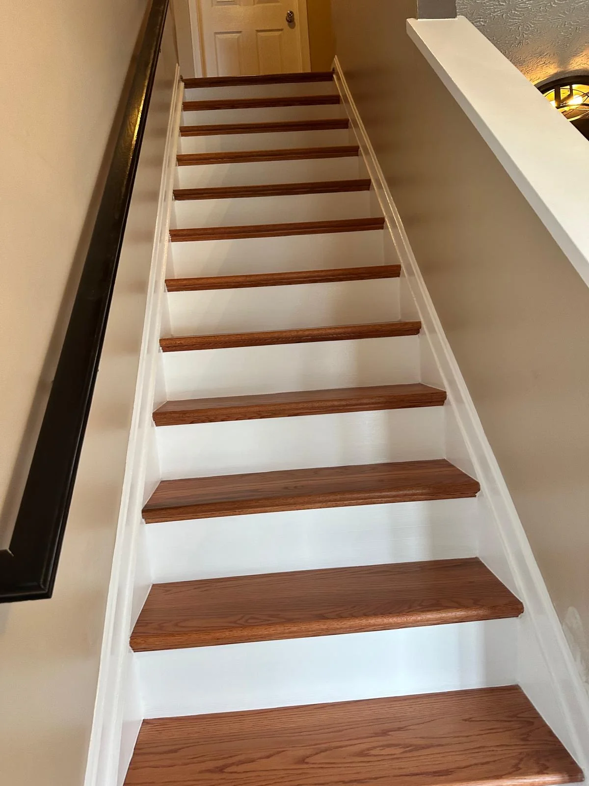 White painted staircase with refinished hardwood treads and white risers in residential interior